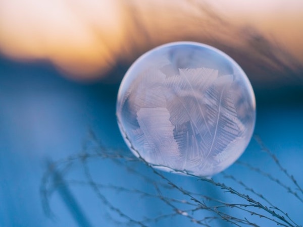 image en gros plan d'une bulle transparente dans un décor d'hiver posée sur des brindilles.